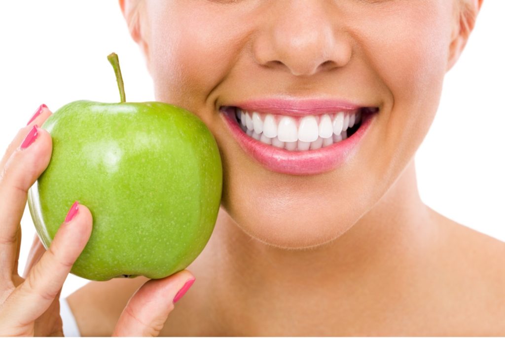 woman smiling with an apple
