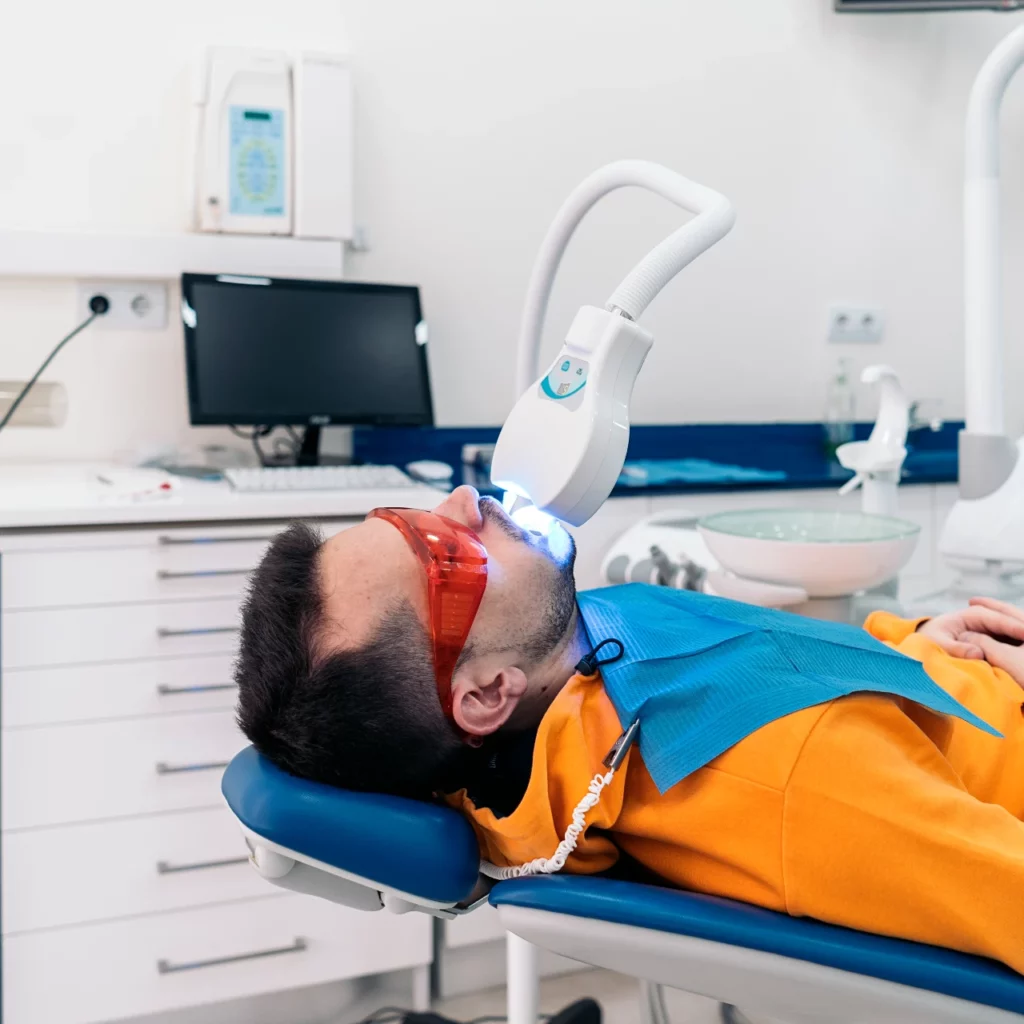 man doing professional teeth whitening at the dentist office